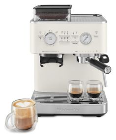 an espresso machine with two cups of coffee next to it on a white background