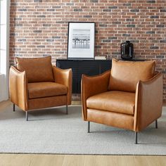 two leather chairs in front of a brick wall