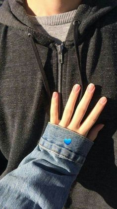 a person wearing a black hoodie with a blue heart on their left hand and a zipper around the wrist