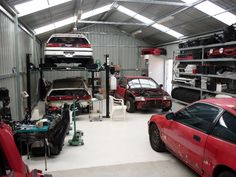 two cars are parked in a garage next to each other and one car is on the lift