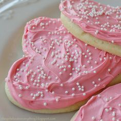 three cookies with pink frosting on a white plate