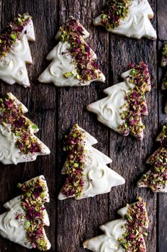 christmas tree shaped cookies with white frosting and sprinkles on a wooden table