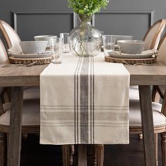 a dining room table set with place settings and flowers in a vase on the table