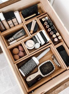 an open drawer containing various beauty products and hair brushes on top of it in a bathroom