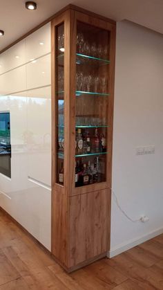 a kitchen with white walls and wooden floors has a glass display case in the center