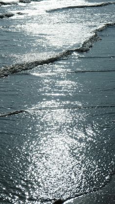 the sun shines on the beach as it reflects off the water's surface