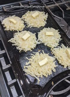 four pieces of cheese sitting on top of a black pan covered in grated cheese