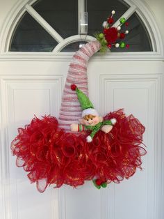 an elf wreath hanging on the front door with red tulle skirt and gnome doll