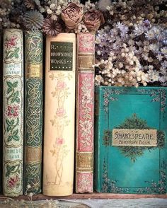 several books are lined up on a shelf next to flowers and other decorative items in front of them