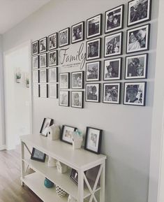 a wall with many family photos and pictures on the wall, along with a table in front of it