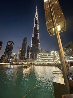 the burj tower is lit up at night in front of other tall buildings