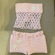 two pieces of crocheted clothing sitting on top of a bed