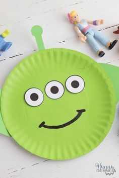 a paper plate with a green monster face on it next to toy figures and toys