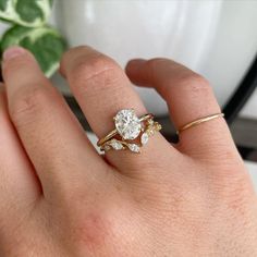 a woman's hand with a gold ring and two diamond engagement rings on it