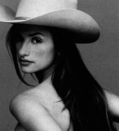 black and white photograph of a woman wearing a cowboy hat with her arms behind her back