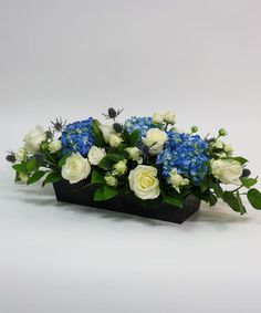 white and blue flowers in a black vase