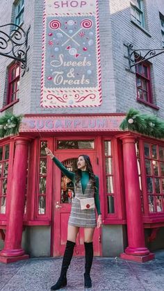 a woman standing in front of a store with her arms up and hands out to the side