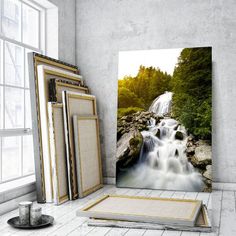 a room with some pictures on the wall and a painting in front of it that has a waterfall