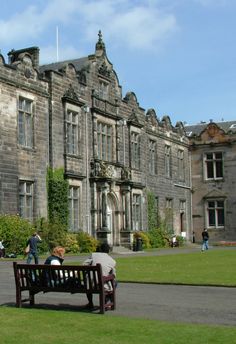 two people sitting on a bench in front of an old building