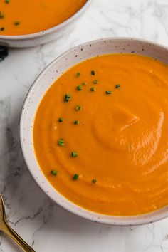 two bowls of carrot soup on a marble table