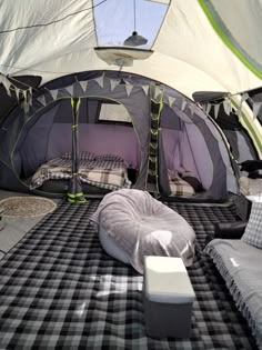 an inside view of a tent with two beds and pillows on the floor, in front of a window