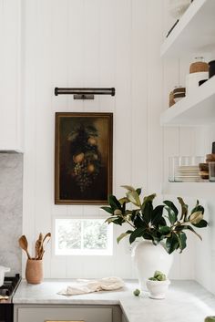 a kitchen with white cabinets and marble counter tops