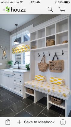 a kitchen with white cabinets and yellow cushions on the bench in front of the sink