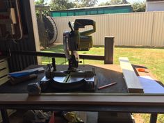 a table that has some tools on it in the middle of a yard with a fence