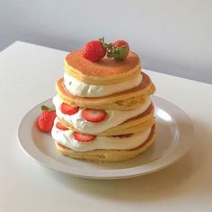 a stack of pancakes topped with whipped cream and strawberries