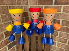 three wooden toy figures sitting on top of each other in front of a brick wall