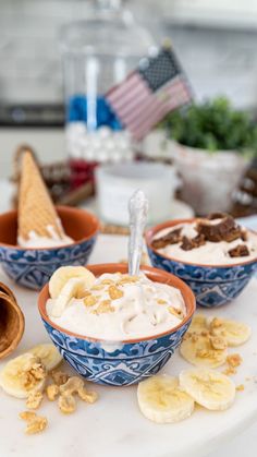 two bowls filled with ice cream and bananas on a table next to other desserts