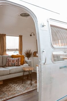 a living room with a couch, coffee table and television inside of an airstream