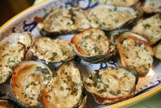 a plate full of cooked oysters with herbs on the top, and cheese on the bottom