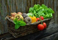 a basket filled with lots of different types of vegetables on top of a wooden table