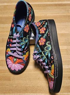 the shoes are decorated with colorful flowers and butterflies on black laces, along with an inner rubber sole