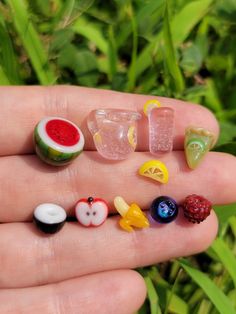 a hand holding several miniature fruits and veggies in it's palm area