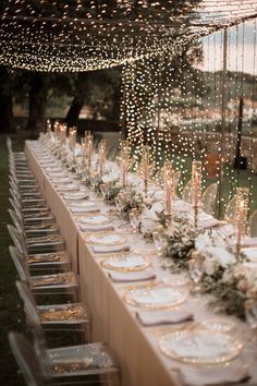 a long table is set up with white plates and silverware for an elegant dinner