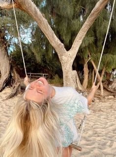 a woman laying on a swing in the sand