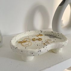 two white vases sitting on top of a table next to each other with gold rings in them