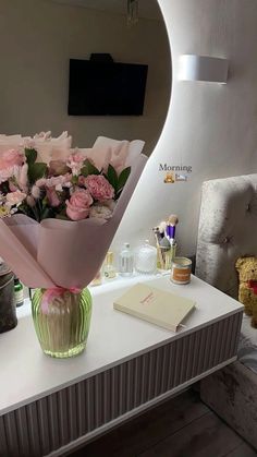 a bouquet of pink flowers sitting on top of a white table next to a mirror