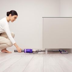 a woman kneeling down on the floor with a vacuum in front of her