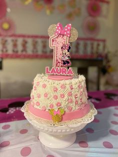 a pink and white cake with minnie mouse topper