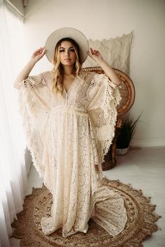 a woman in a white dress and hat sitting on a rug