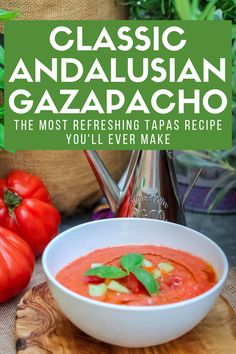 a bowl of gazpaca sitting on top of a cutting board next to tomatoes