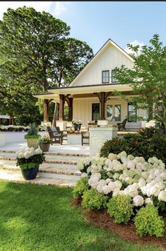 a house with white flowers in the front yard and steps leading up to the porch