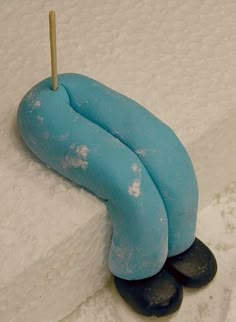 a blue sculpture sitting on top of a snow covered ground next to a wooden stick