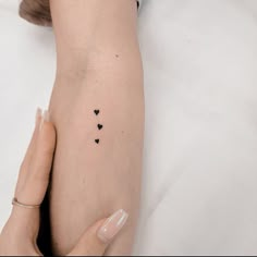 a woman's arm with small black hearts on the left side of her arm