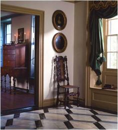 a room with a checkered floor and two paintings on the wall next to a window