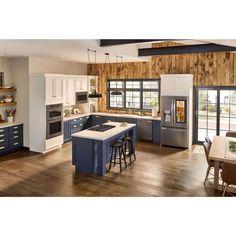 a kitchen with blue and white cabinets, an island in the middle and wood paneling on the walls