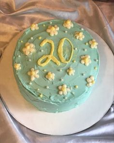 a green cake with white flowers and the number 90 on it is sitting on a plate